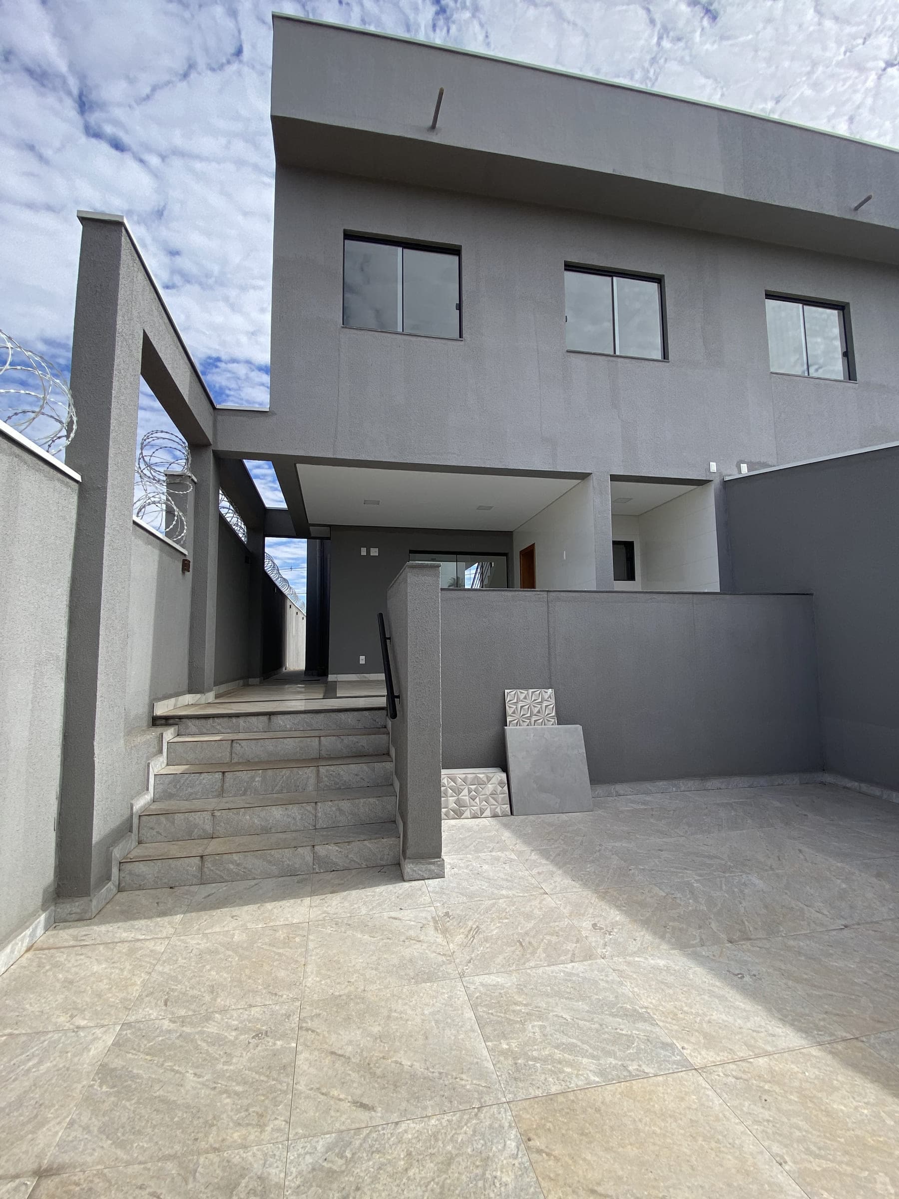 Área externa da casa, com escada de acesso ao terraço e piso em porcelanato.