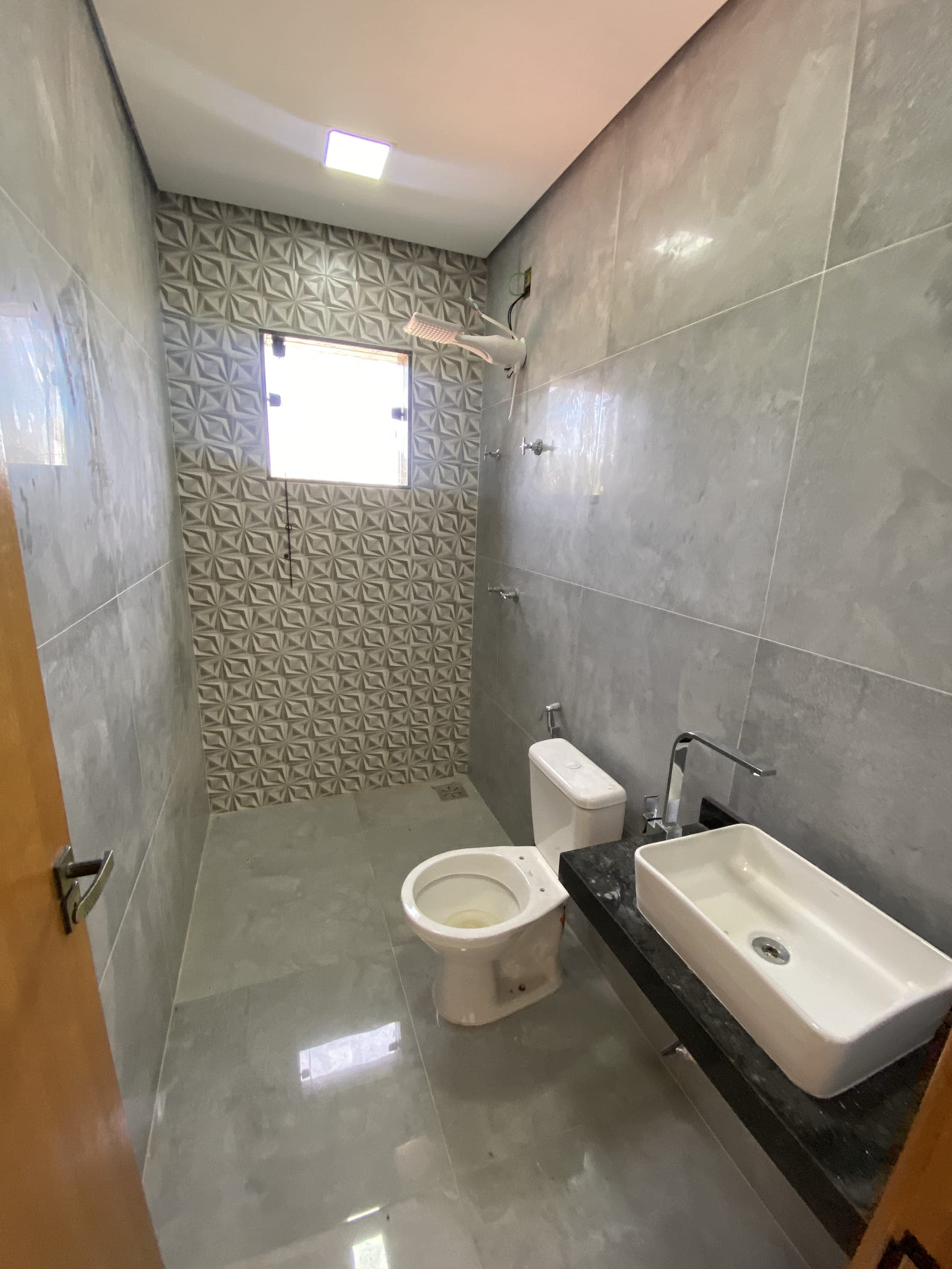 Banheiro social, com bancada em granito, cuba de apoio e área de banho.
