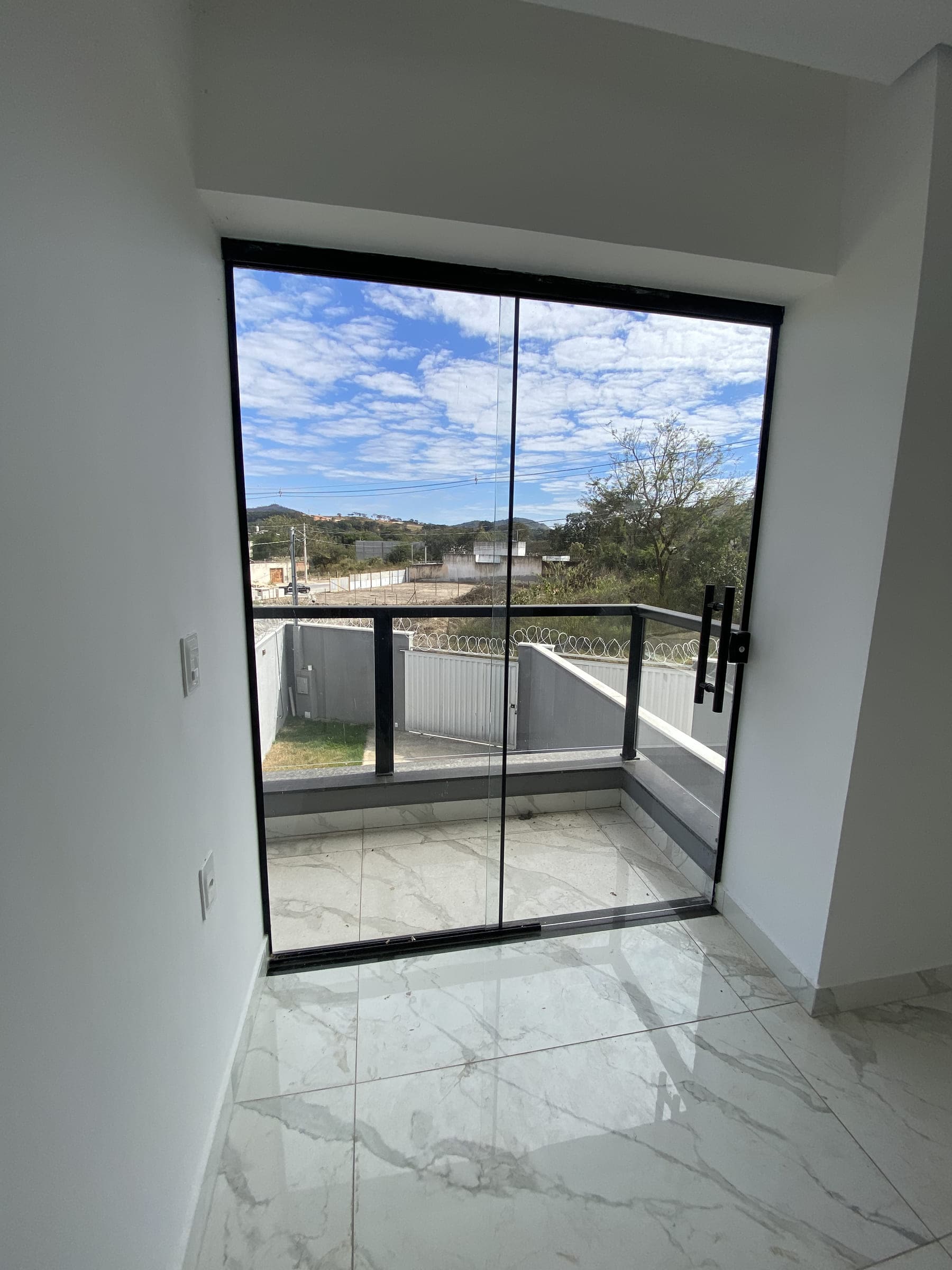 Varanda da suíte, com guarda-corpo de vidro e vista aberta para o horizonte.